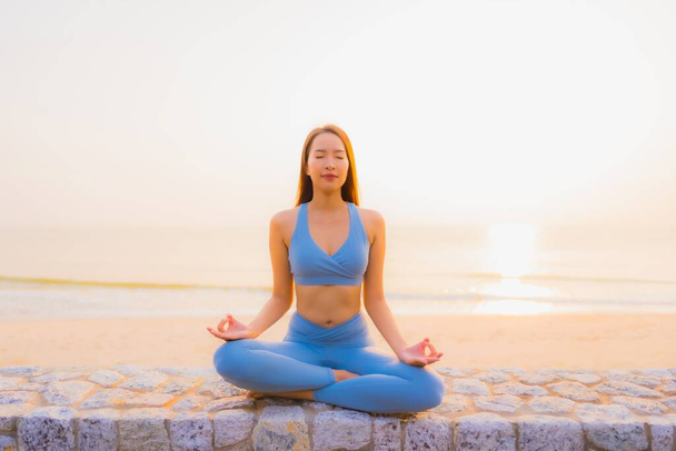 Portret jonge aziatische vrouw doen meditatie rond zee strand oceaan bij zonsopgang voor de gezondheid - Foto, afbeelding
