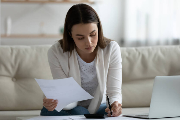 Focused young woman planning mortgage payments at home. - Foto, afbeelding