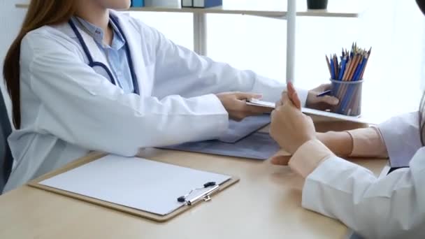 Hastane sağlık tedavi kliniğinde uzman doktorlara danışmanlık yapan iki kadın doktor. Doktor, dizüstü bilgisayar kullanarak onkolog tedavisi için reçete yazıyor..  - Video, Çekim
