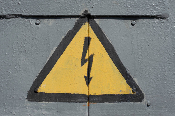 Het waarschuwingsbord voor hoogspanning is op de metalen deur van de transformator geschilderd. - Foto, afbeelding