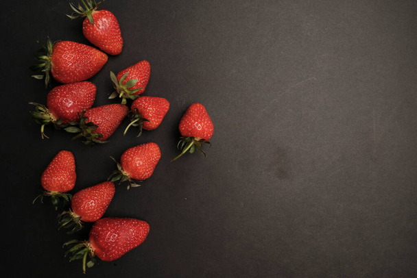 Red strawberries on dark chalkboard with copy space - 写真・画像