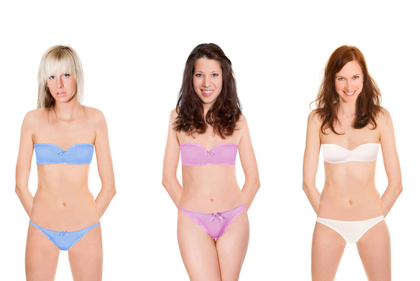 Drei attraktive Models tragen Dessous in verschiedenen Farben, isoliert vor weißem Studiohintergrund - Foto, Bild