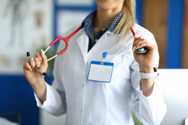 Medical officer in white coat holds stethoscope. - Foto, afbeelding
