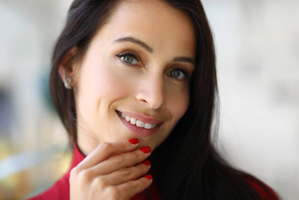 Porträt einer lächelnden brünetten Frau mit roter Maniküre - Foto, Bild