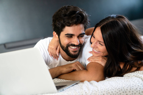 Happy young couple relaxing at home with laptop. Love, happiness, people and fun concept. - Φωτογραφία, εικόνα