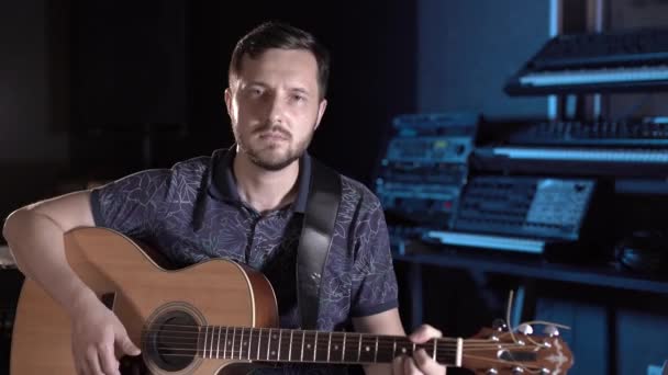 handsome guitarist with beard plays acoustic guitar in a music studio. Closeup - Footage, Video