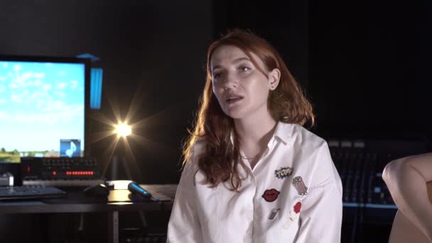 Plan moyen de belle jeune femme aux cheveux roux chantant et regardant la caméra dans un studio de musique - Séquence, vidéo