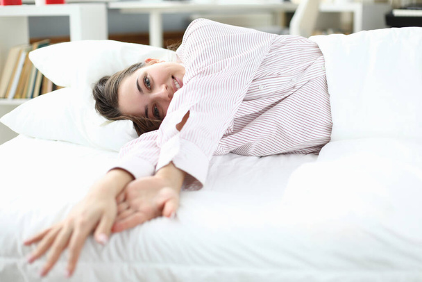 Nainen makaa sängyssä paidassa ja hymyilee. lähikuva - Valokuva, kuva