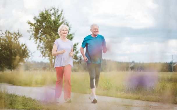 sprawna i aktywna para seniorów biegająca na świeżym powietrzu jako ćwiczenie - Zdjęcie, obraz