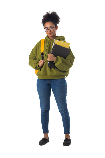 Friendly ethnic black female high school student in eyeglasses with backpack and composition book isolated on white background, full length portrait - Фото, изображение