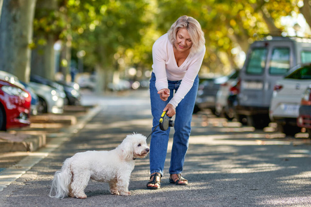 Ηλικιωμένη γυναίκα περπατά με ένα σκυλί σε εξωτερικούς χώρους. - Φωτογραφία, εικόνα