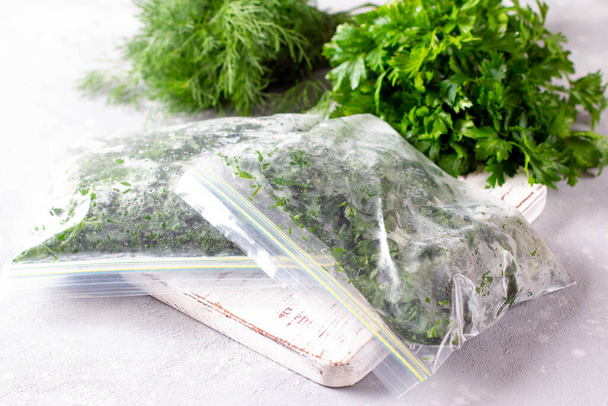 Mrożone zioła (koperek i pietruszka) w plastikowej torbie. Mrożone warzywa. Pojęcie zdrowego odżywiania. - Zdjęcie, obraz