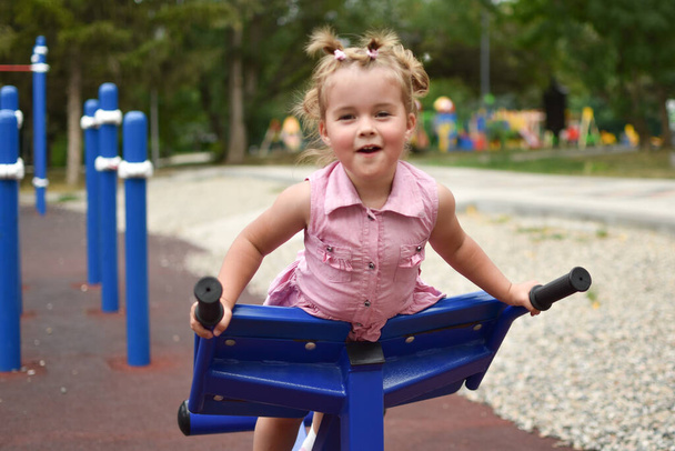 Baby lachend klein meisje op de speelplaats. Jonge leuke sportvrouw. - Foto, afbeelding