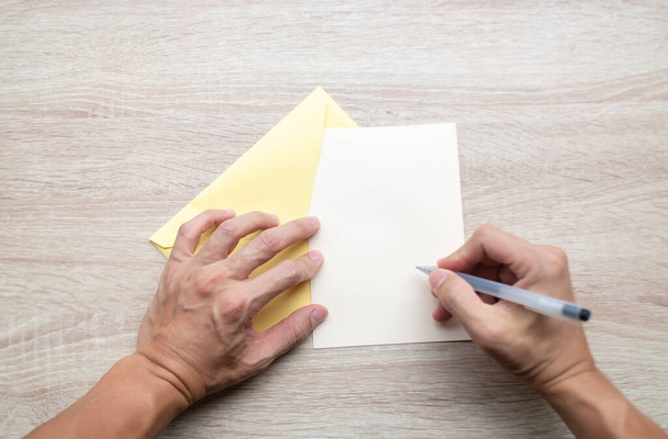 Αρσενικά χέρια που γράφουν άδειες κάρτες σε ξύλινο τραπέζι. - Φωτογραφία, εικόνα