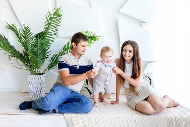 mladí maminka a tatínek drží dítě, rodiče s dítětem na fotografii Studio, rodinný den, šťastná rodina - Fotografie, Obrázek