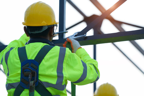 Trabajadores de la construcción que usan cinturón de arnés de seguridad trabajando en un lugar alto en la obra. - Foto, Imagen