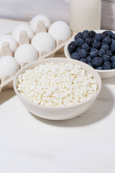 fresh farm products, cottage cheese, milk, blueberries and eggs on a white background, vertical - Zdjęcie, obraz