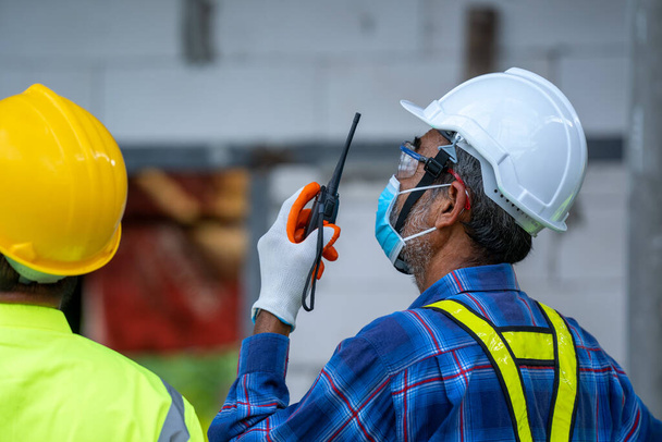 Інженер, який носить захисну маску для захисту від Ковид-19 і перевіряє виробничий процес на будівельному майданчику Інженер, Концепція будівництва, Коронавірус перетворився на глобальну надзвичайну ситуацію. - Фото, зображення