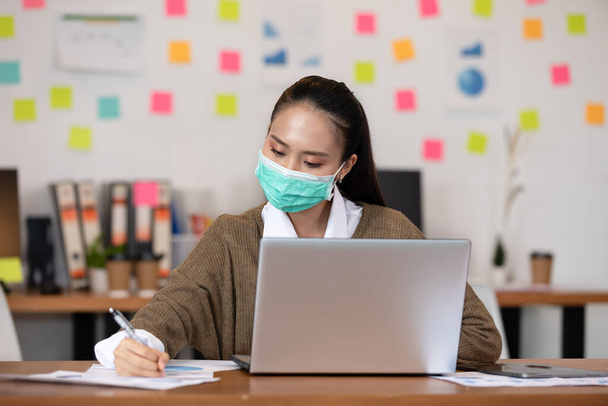 Happy Asian business woman wearing face mask looking laptop working at modern office or Co-Working Space,Business Startup Concept - Valokuva, kuva