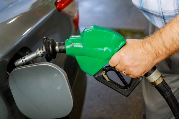 Man pompt benzine auto bij tankstation wordt gevuld met brandstof op close-up - Foto, afbeelding