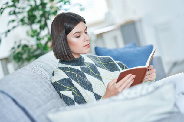 Adolescente lisant un livre à la maison - Photo, image