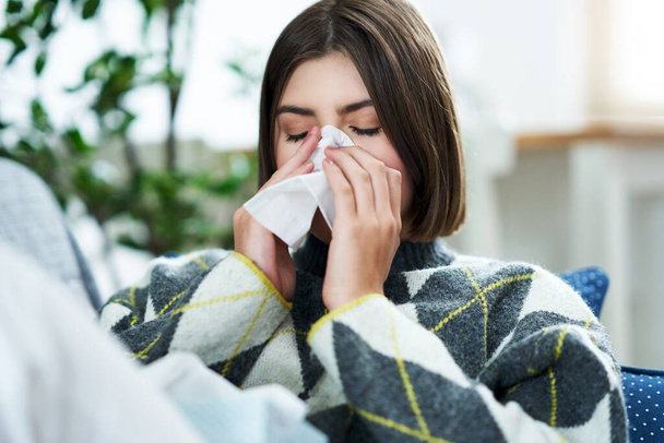 Teenager sneezing in a tissue in the living room - Photo, Image