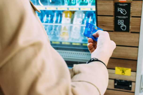 close-up of a woman using her credit card to pay at the vending machine - Photo, Image