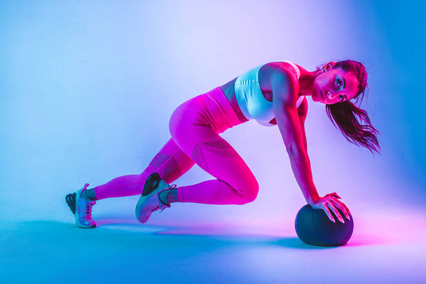 Athletic woman with fitness sportswear traning - Beautiful girl doing fitness in a studio - 写真・画像
