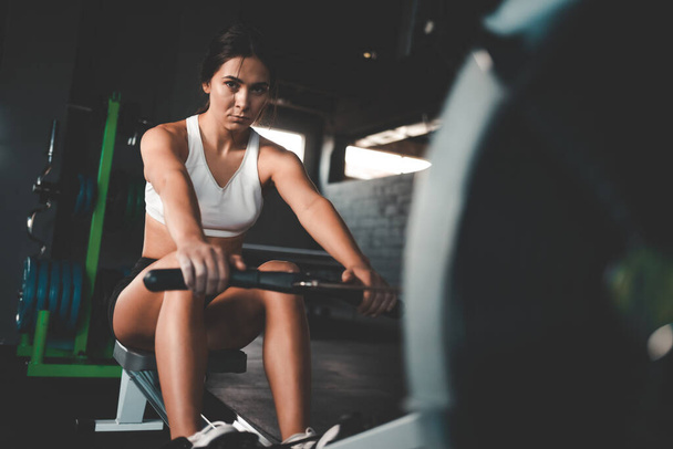 Συγκεντρωμένη αθλητική κοπέλα κάνει άσκηση στη μηχανή κωπηλασίας - Φωτογραφία, εικόνα