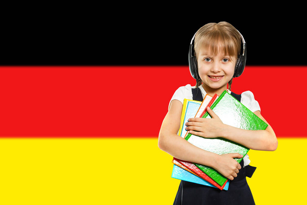 Glückliches junges Mädchen mit Büchern, auf dem Hintergrund der Deutschlandfahne. Das Konzept des Spracherwerbs und des Studiums. Reisen. - Foto, Bild