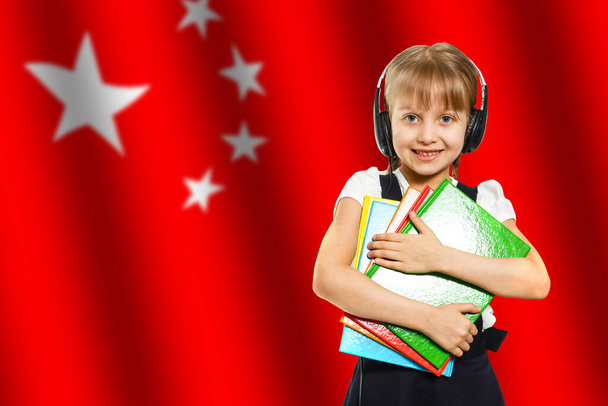 Çin bayrağının arka planında kitapları tutan mutlu genç kız. Dil öğrenme ve öğrenme kavramı. Seyahat. - Fotoğraf, Görsel
