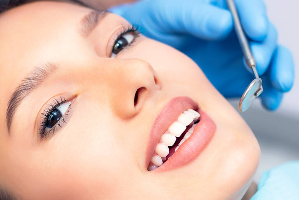 Attractive young woman in a dental clinic with a male dentist. Healthy teeth concept. - 写真・画像