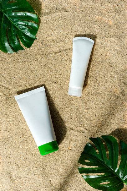 Mock-up tubos de plástico crema sobre un fondo de playa de arena. - Foto, imagen