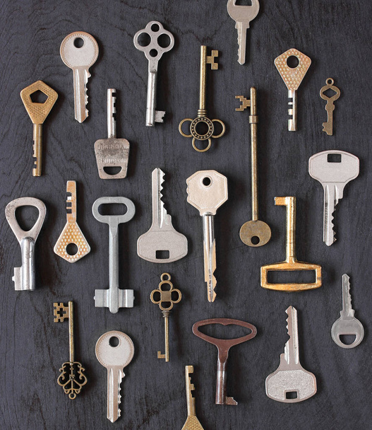 various metal keys on a black wooden background, top view. flat lay. - Zdjęcie, obraz