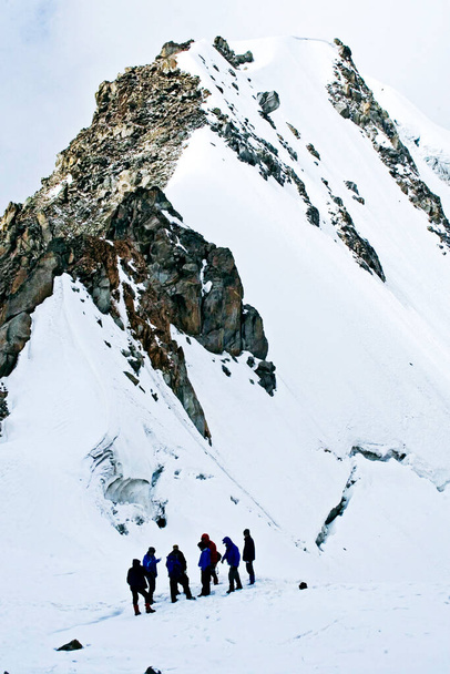 grupa wspinaczy przy zaśnieżonym klifie, wspinająca się na wieczorne chmury Elbrus, na wysokości 4 tys. metrów - Zdjęcie, obraz