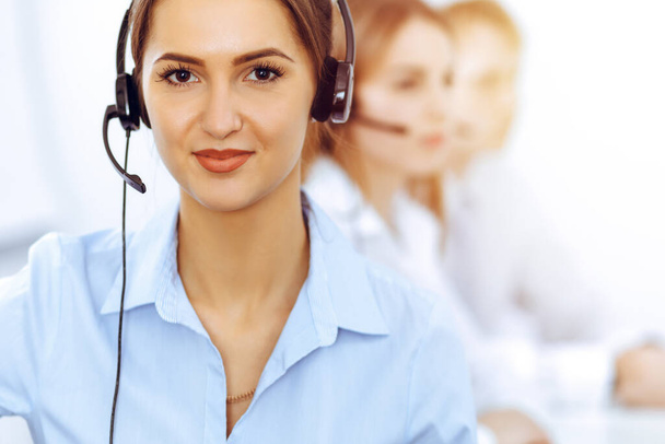 Call center operators. Focus on beautiful business woman using headset in sunny office - Foto, Imagem