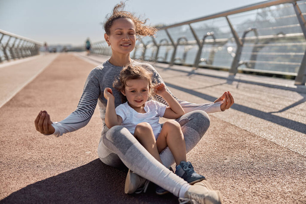 happy healthy and sporty mom and daughter are doing workout trainings in sunny day - Fotó, kép
