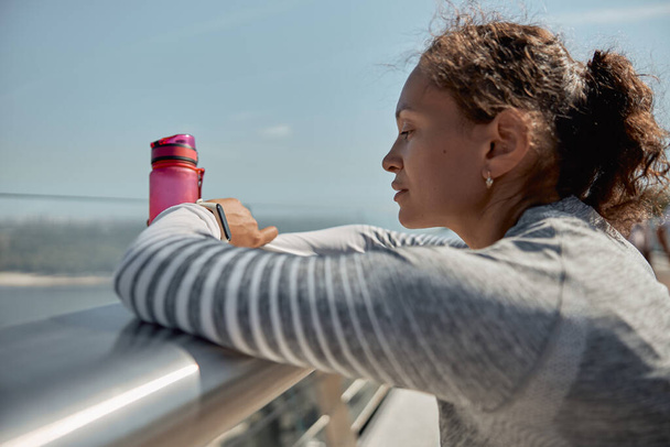 健康でスポーティな女性は晴れた日にトレーニングした後に水を飲んでいます - 写真・画像