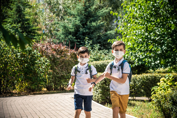 Счастливые школьники в масках бегут от радости возвращения в школу во время карантина Ковид-19. - Фото, изображение