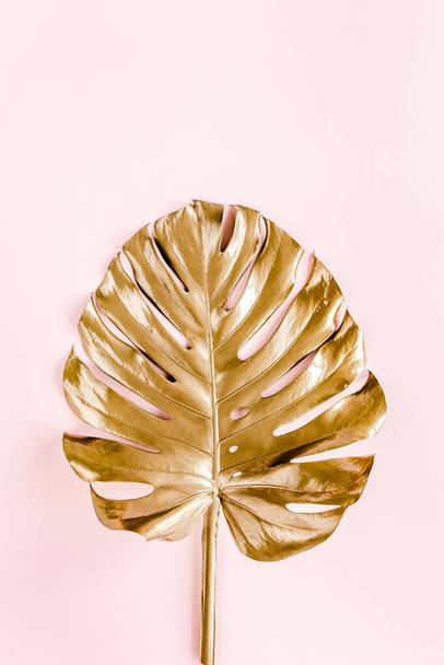 Золотые тропические пальмовые листья Monstera на розовом фоне. Плоская кладка, вид сверху минимальная концепция. - Фото, изображение