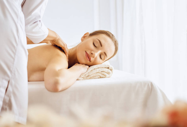 Beautiful woman enjoying back massage with closed eyes. Spa treatment concept - Fotografie, Obrázek