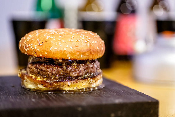 Ένα κλασικό Burger με μια κοτολέτα βρίσκεται ανάμεσα σε δύο ψωμάκια σουσάμι. - Φωτογραφία, εικόνα