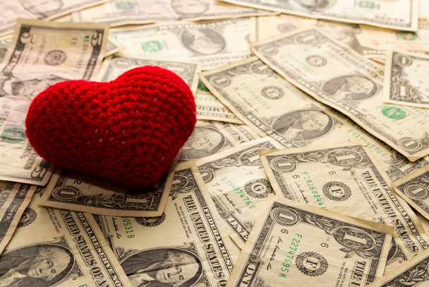 Κόκκινη καρδιά υφασμένη σε χαρτονομίσματα του δολαρίου, αγάπη για το χρήμα. - Φωτογραφία, εικόνα