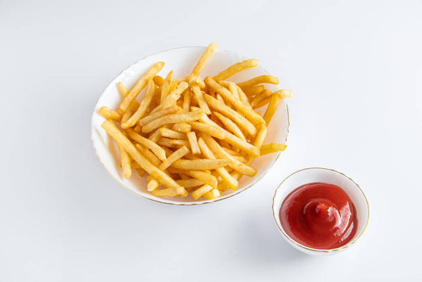 Crispy fries in a plate on a white background. Hot american fast food. - 写真・画像