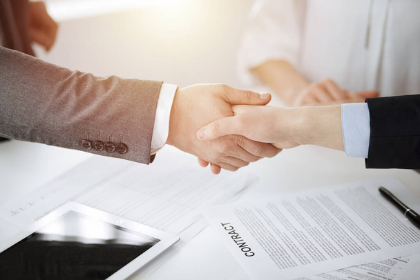 Business people shaking hands finishing contract signing in sunny office, close-up. Handshake and marketing - Valokuva, kuva