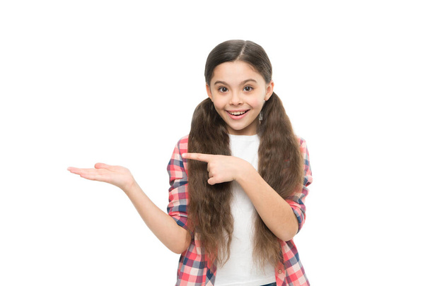 Looking trendy. happy child pointing finger, copy space. little beauty casual style. small girl isolated on white. kid in checkered shirt and jeans. care about long hair health. pure beauty of young - Foto, immagini