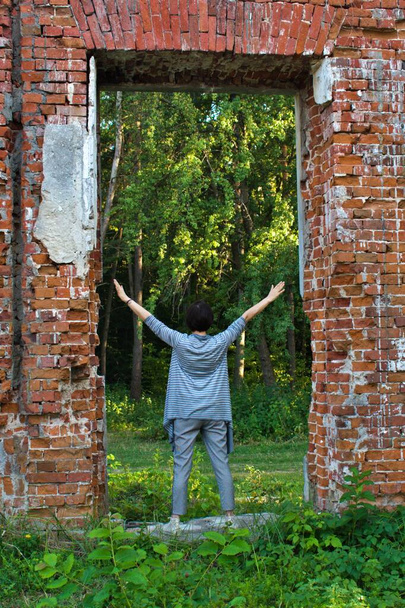 woman with raised arms up in the opening of brick wall - Photo, Image