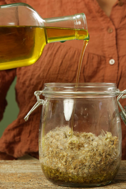 Жінка робить трав'яну олію з жовтими квітками безсмертних. Процес мацерації натуральної косметики
. - Фото, зображення