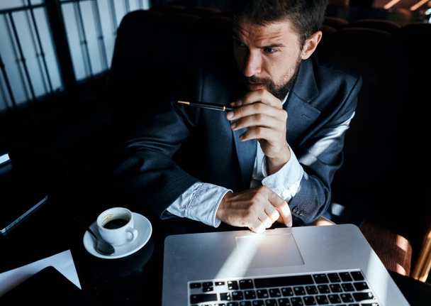 Uomo d'affari seduto in un caffè di fronte a un computer portatile con una tazza di caffè lavoro tecnologia stile di vita - Foto, immagini