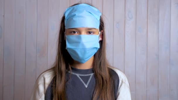 Portrait of a beautiful dark haired school girl wearing protective medical face mask on forehead. Protection concept. Girl female lady preventing against virus corona. Social distancing, quarantine. Funny use of disposable masks. - Footage, Video